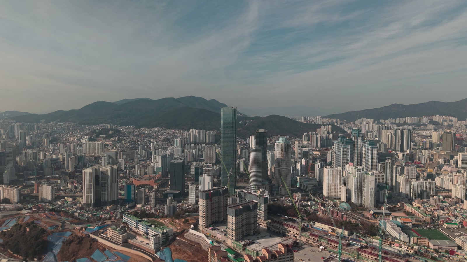 산자락 아래 아파트와 주택이 빼곡한 문현동 전경, 가운데 부산국제금융센터 건물이 솟아 있는 모습